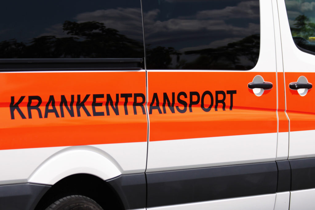 Auto mit einem orangen Streifen auf der Seite, wo in schwarz Krankentransport draufsteht