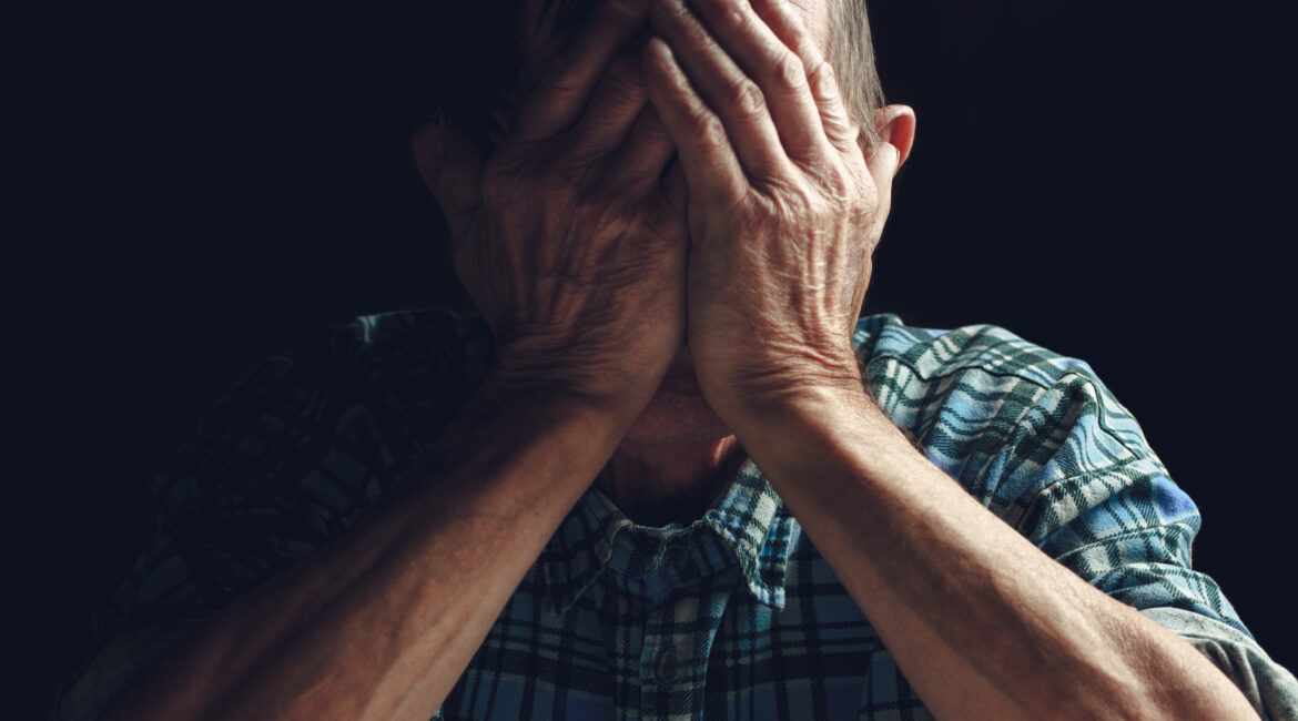 Älterer Mann mit Alzheimer Krankheit hält Hände vor das Gesicht